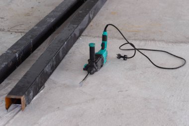 Perforatör beton zeminde yatıyor. İnşaat alanındaki dev borular. Çalışma aracı fotoğrafı.