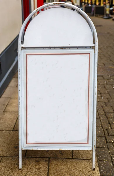 White metal placard placed on the floor in the street