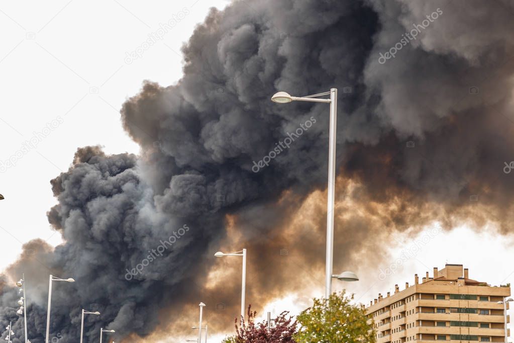 The smoke of a huge fire flooding the sky of a city