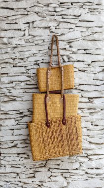 Beyaz bir duvarda asılı üç hasır Çantalar