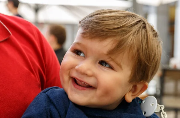 Un niño lindo y sonriente en los brazos de un adulto —  Fotos de Stock