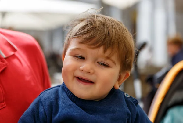 Un niño lindo sonríe mientras está en los brazos de un adulto — Foto de Stock