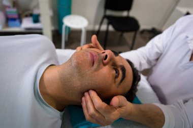 Bir terapist bir adamın yüzünü kenarlarında masajlar