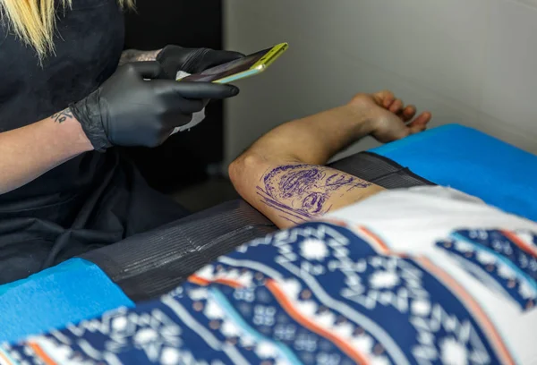 A blonde tattooist photographing the tattoo she is doing to her — Stock Photo, Image