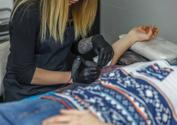 Bir dövmeci sarışın kız bir dövme bir küçük ve şirin studi çizer. — Stok fotoğraf
