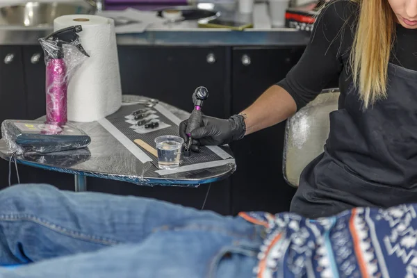 Bir dövmeci kız bir istemci kolundaki dövme çizim — Stok fotoğraf