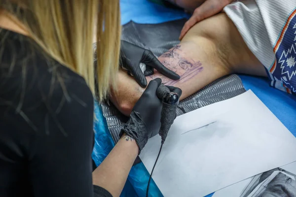 A tattoo artist is designing a tattoo on the arm of a boy — Stock Photo, Image