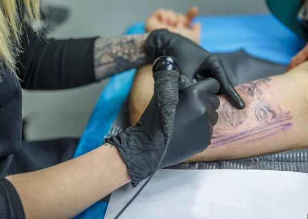 Blonde vrouw schetst een tatoeage met haar tattoo machine — Stockfoto