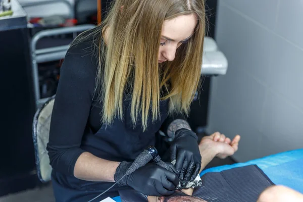 Szőke lány ábrázolja egy tetoválás az ő tetováló gép — Stock Fotó