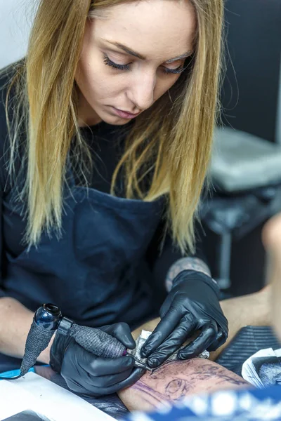 Mooie blonde kunstenaar is het maken van een tatoeage met maximale concentratie — Stockfoto