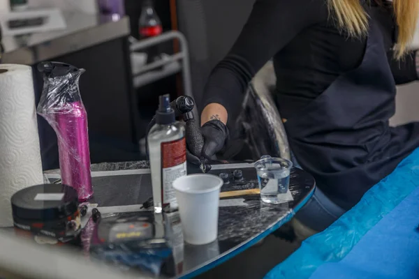 Een tatoeëerder is het oppakken van inkt voor een tattoo in haar atelier — Stockfoto