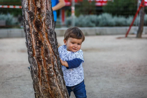 Nabídka dítě hraje vedle stromu v parku — Stock fotografie
