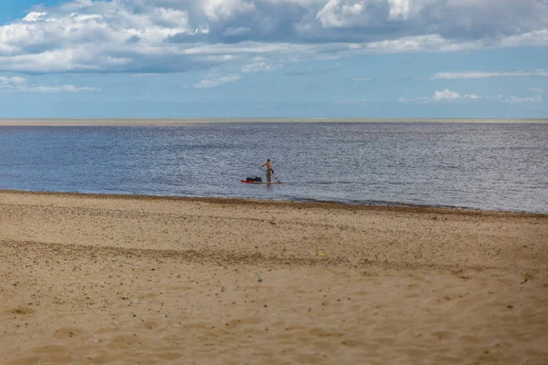 Ένας μοναχικός άνθρωπος που πλέει κοντά στην ακτή του μια όμορφη και ήσυχη παραλία — Φωτογραφία Αρχείου