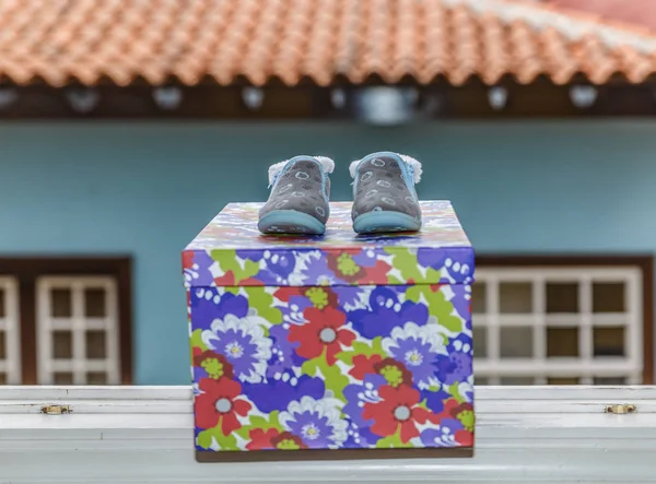 Chaussures de bébé sur un coffret cadeau sur le rebord d'une fenêtre — Photo