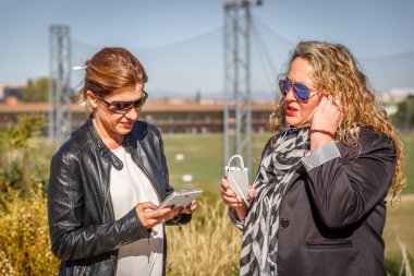 İki kadın ceketler sohbet sokakta, bir tanesi ise kontrol