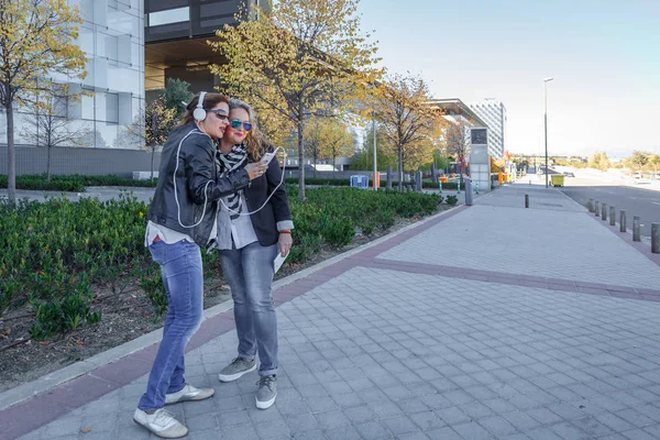 Deux amies écoutent de la musique dans une rue — Photo