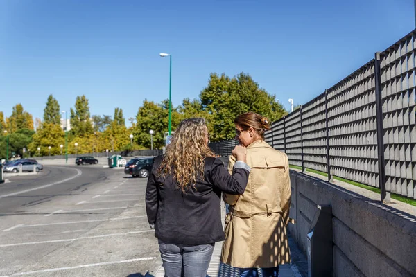 Two friends walk and talk quietly on a sunny day