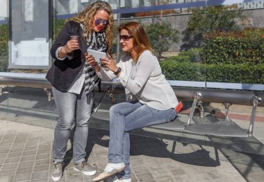 Bir mobil cihaz, bir otobüs sto beklerken iki arkadaşları inceleme