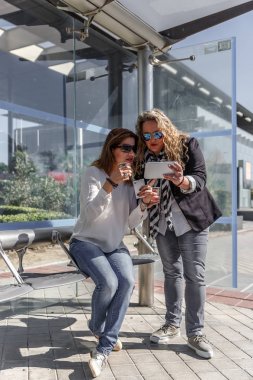 İki iş kadınları sohbet ve bir otobüs beklerken kahve