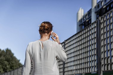 Cep telefonu bahseden bir ince kadın arkadan görünüm