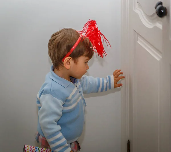 Маленький мальчик с красными рогами приближается к двери в своем доме — стоковое фото
