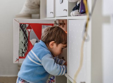 Küçük bir çocuk oyuncaklarını bir dolap içinde arar