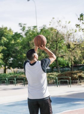 Elinde basketbol topu olan bir atlet sepete atmaya hazırlanıyor.