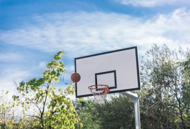 Şehir basketbol sahasının basketbol tahtası ve havadaki top manzarası.
