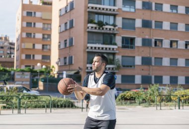 Güçlü basketbolcu, şehir kortunun ortasında potaya iyi bir atış yapmaya hazırlanıyor.
