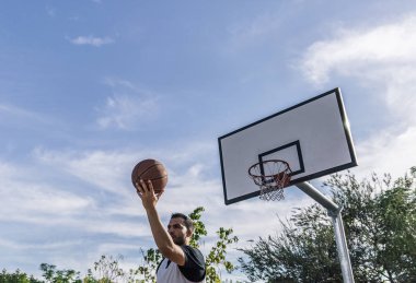 Basketbolcu topu sırtında bir dış saha potasına fırlatıyor.
