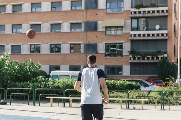 Urban basketball player running behind a ball on a city court