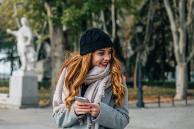 Beautiful caucasian blonde girl with coat and scarf looks aside 