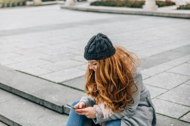 Young caucasian blond woman writes a message on her mobile phone