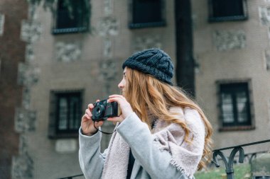 Blonde girl with a hat holds in her hands an old vintage camera 