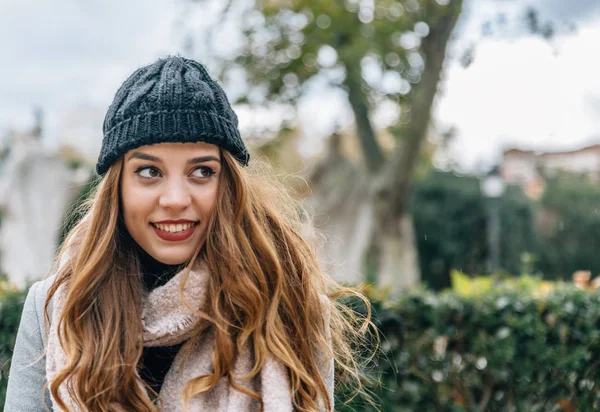 Portrait placé sur le côté gauche d'une jeune fille blonde avec un chapeau de laine souriant à l'extérieur — Photo