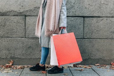 View of the legs of a woman wearing coat and jeansm next to her 
