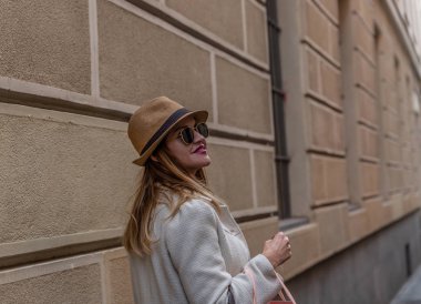 Caucasian woman with hat and coat walks through an ancient city