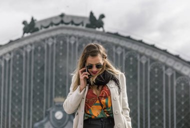Business woman with black glasses coat and shirt speaks on her smartphone in a big city