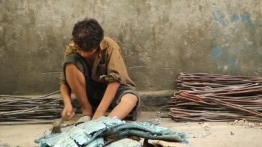 PAKISTAN - GUJRANWALA 2014: Pakistan 2014 Gujranwala 'da keskin çekiç yardımıyla bakır boruları araba radyatörlerinden ayıran bir çocuk