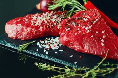 Yakın çekim taze sığır eti biftek ile karanlık bir arka plan üzerine baharat için