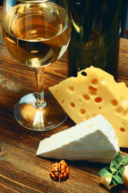 Peynir ve şarap bir bardak bir ahşap tahta üzerinde.