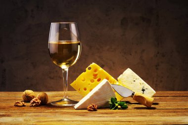 Peynir ve şarap bir bardak bir ahşap tahta üzerinde.
