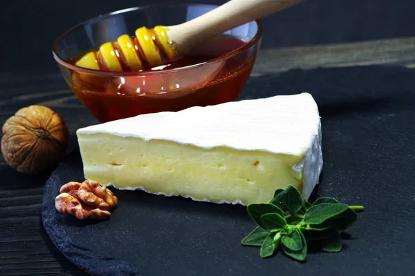 Un pezzo di brie cheese con miele su sfondo scuro . — Foto Stock