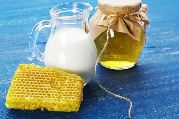 Honing met melk op een blauwe oude bord. — Stockfoto