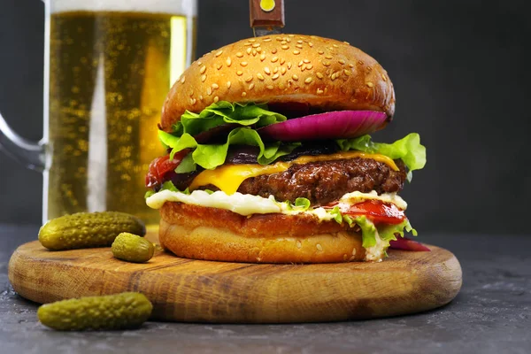 Close-up de delicioso hambúrguer de carne em uma tábua de madeira com um copo de cerveja . — Fotografia de Stock