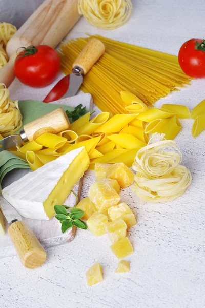 Pâtes et fromage avec divers ingrédients pour cuisiner sur un fond rustique léger . — Photo