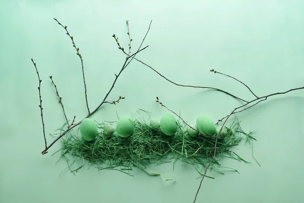 Œufs de Pâques peints dans un nid décoratif sur un fond vert pastel. Vue de dessus. Pose plate. Pastels punchy . — Photo