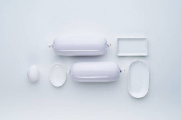 Top view of the composition of white dishes and sausages in a laconic style. Flat lay.