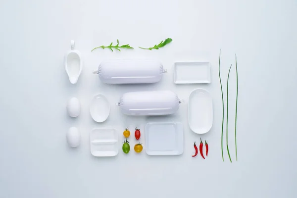 Vedere de sus a compoziției mâncărurilor albe și cârnaților, cu adăugarea de legume miniaturale multicolore într-un stil laconic. Plat lay . — Fotografie, imagine de stoc
