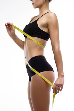 Şeklin parametrelerini ölçen, iç çamaşırlı beyaz arka plandaki kız.